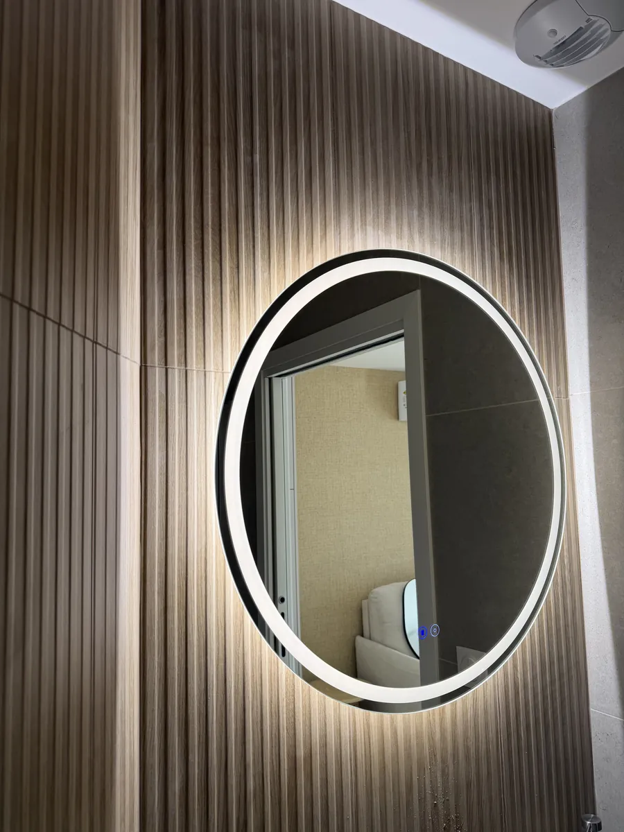 Miroir rond rétroéclairé sur un mur à lames