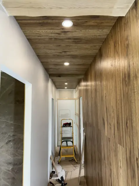 Couloir éclairé par des spots encastrés dans un plafond en bois