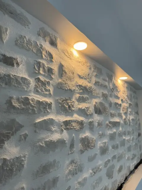 Mur en pierre mis en valeur par des spots encastrés